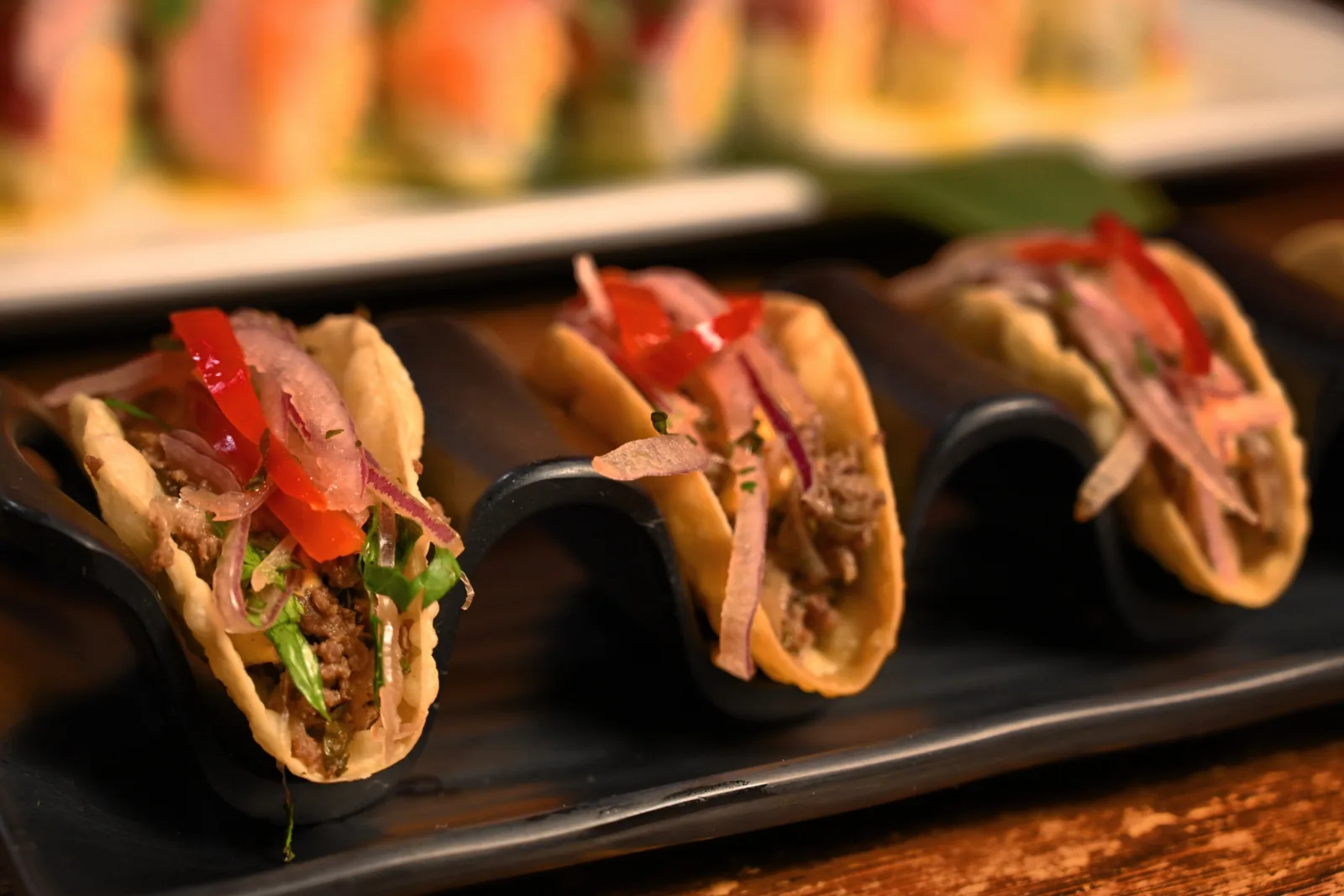 Pork belly tacos plated on a black stand